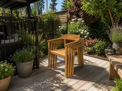 Stacked Veluta Curve FSC® certified teak outdoor dining chairs on a contemporary garden deck, ideal for patio dining
