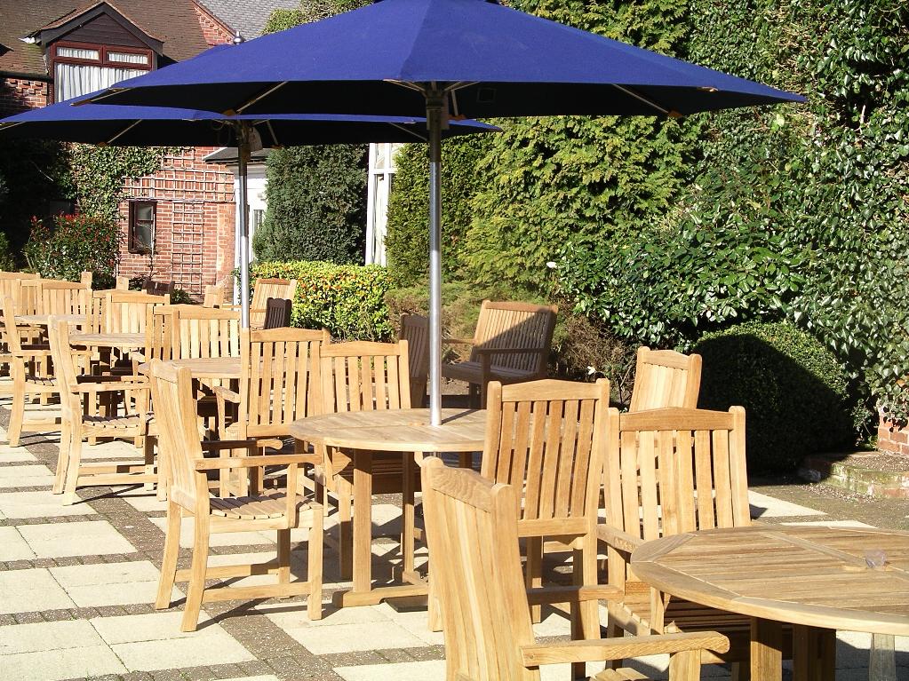 Teak round table and chairs shining a rich golden brown in the afternoon sun at The Belfry. 