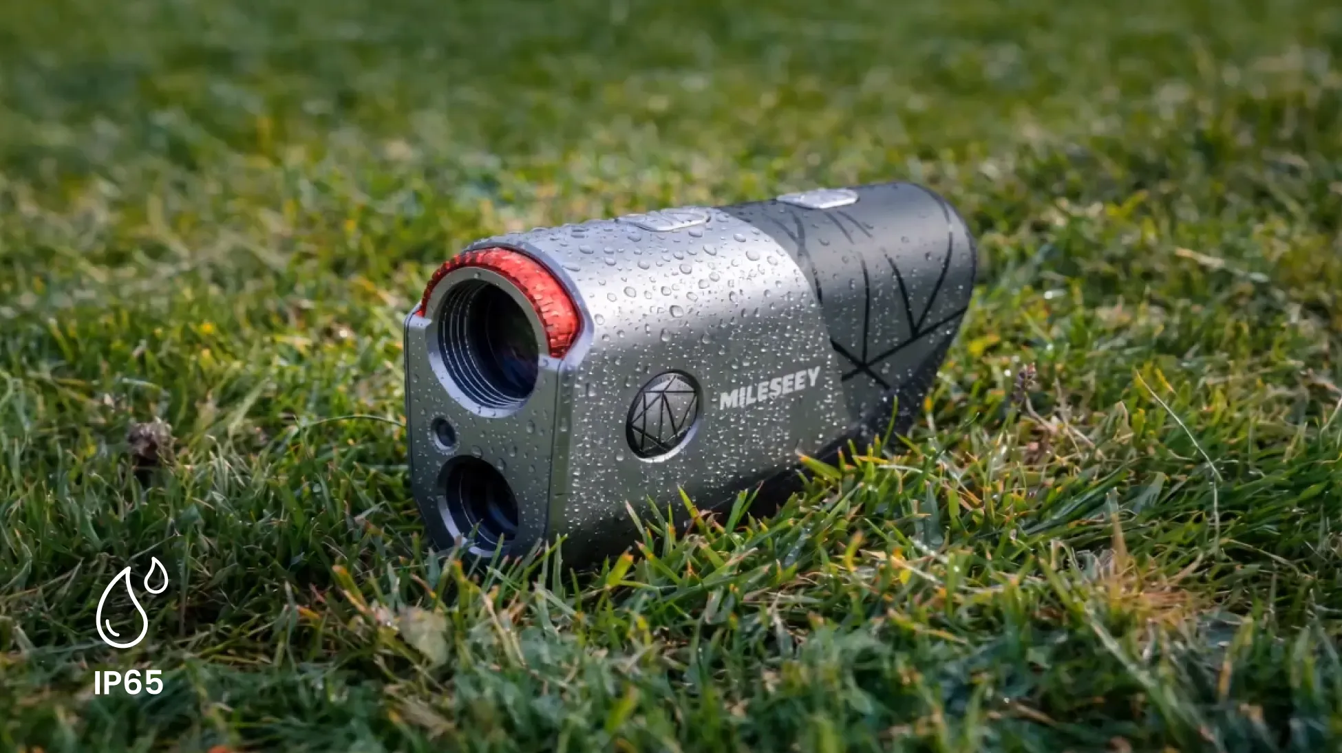 Mileseey GenePro S1 rangefinder covered in water droplets on wet grass, IP65 water resistance icon in the corner
