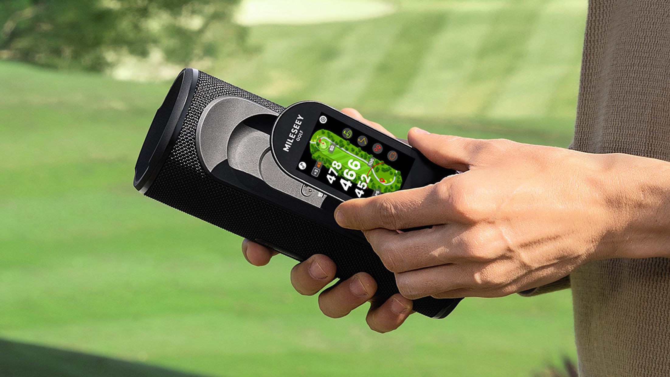 Golfer holding the MILESEEY GeneSonic Pro Detachable GPS Speaker with the GPS handheld docked in the speaker base on the course