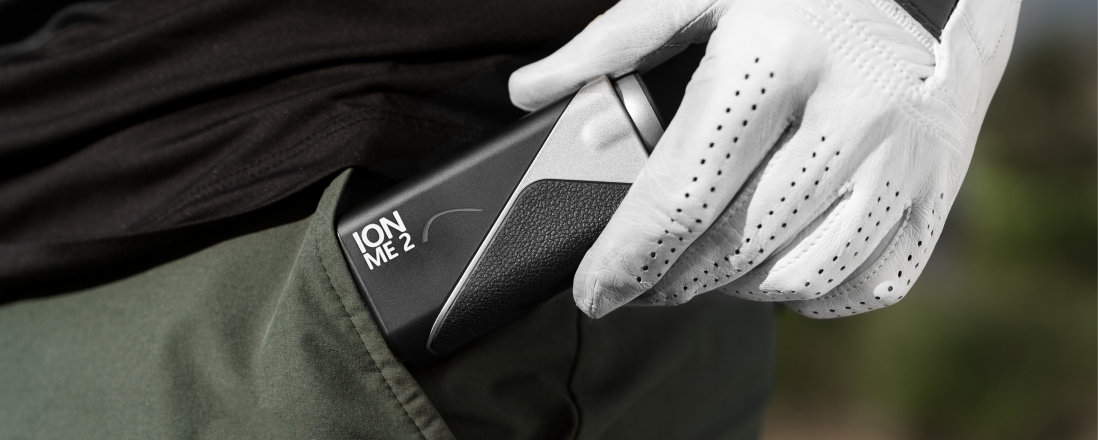 Gloved hand pulling the Mileseey IONME2 rangefinder from a green pants pocket