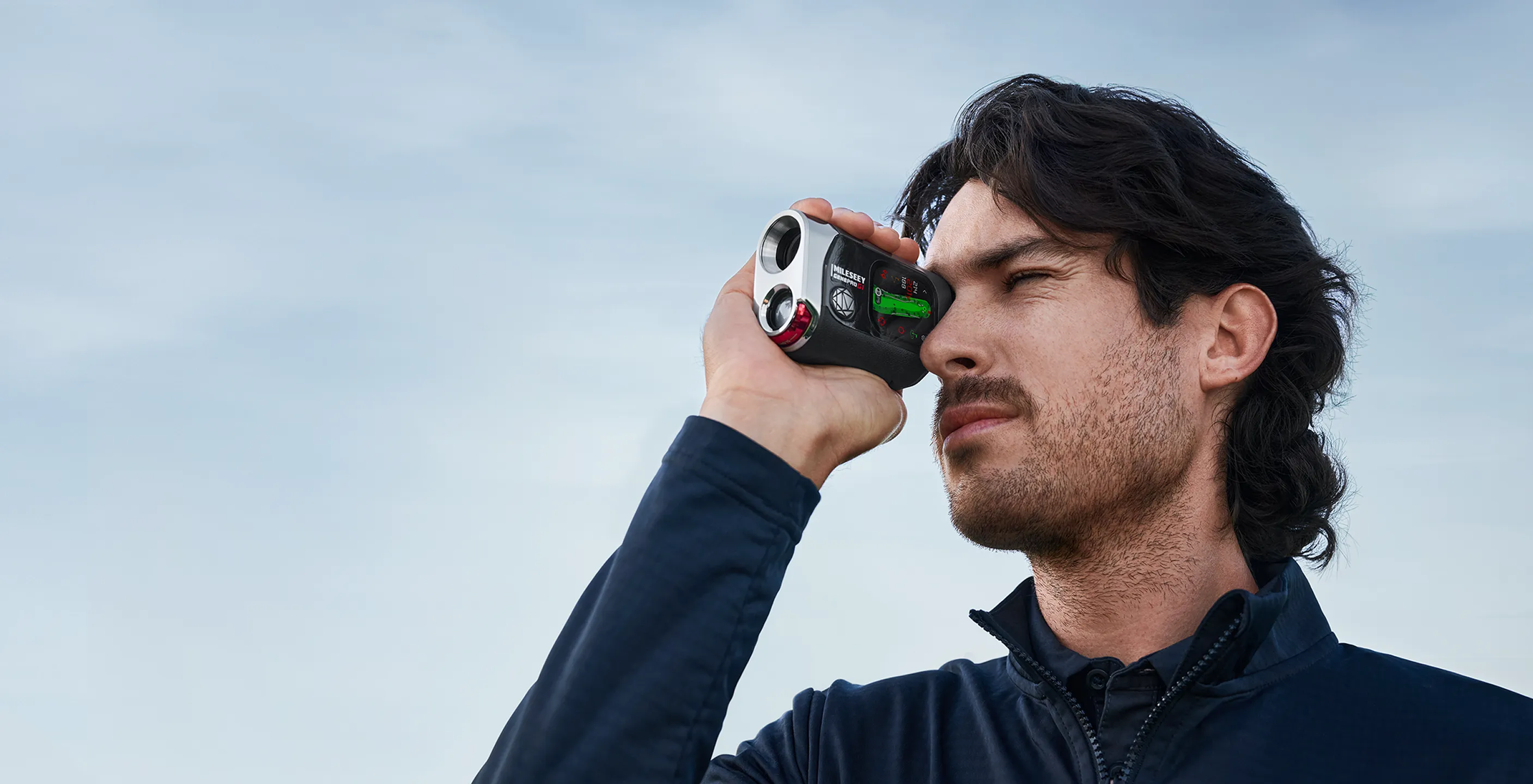Golfer raising the Mileseey GenePro G1 rangefinder to his eye to aim at a distant flag