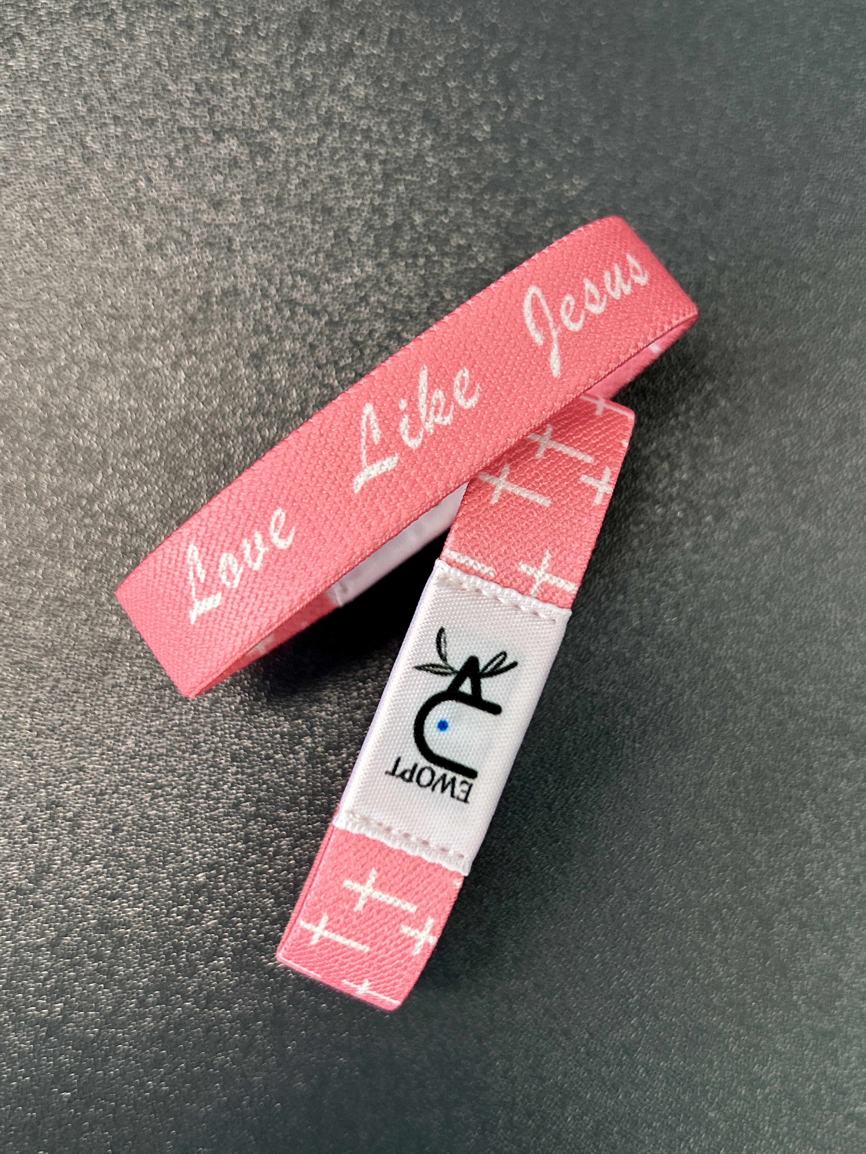 {"default":"A waterproof Yappybracelet wristband by EWOPT featuring a vibrant pink design adorned with white crosses and the inspirational text \"Love Like Jesus.\" Crafted with durable, waterproof materials, the wristband includes NFC functionality for seamless access to Daily Bible content. "}