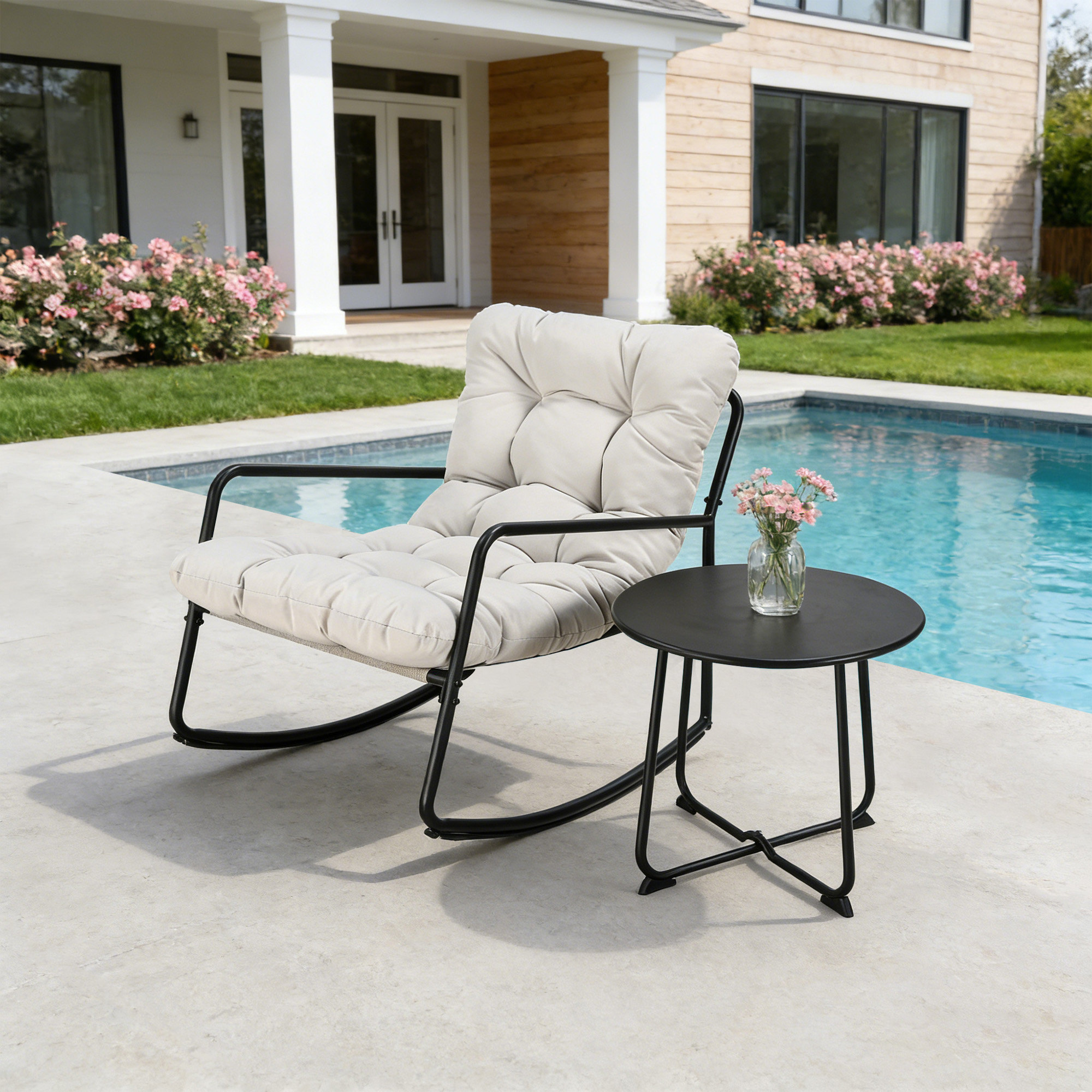 Modern metal patio rocking chair with plush cushions beside a round black side table by pool-Seehill
