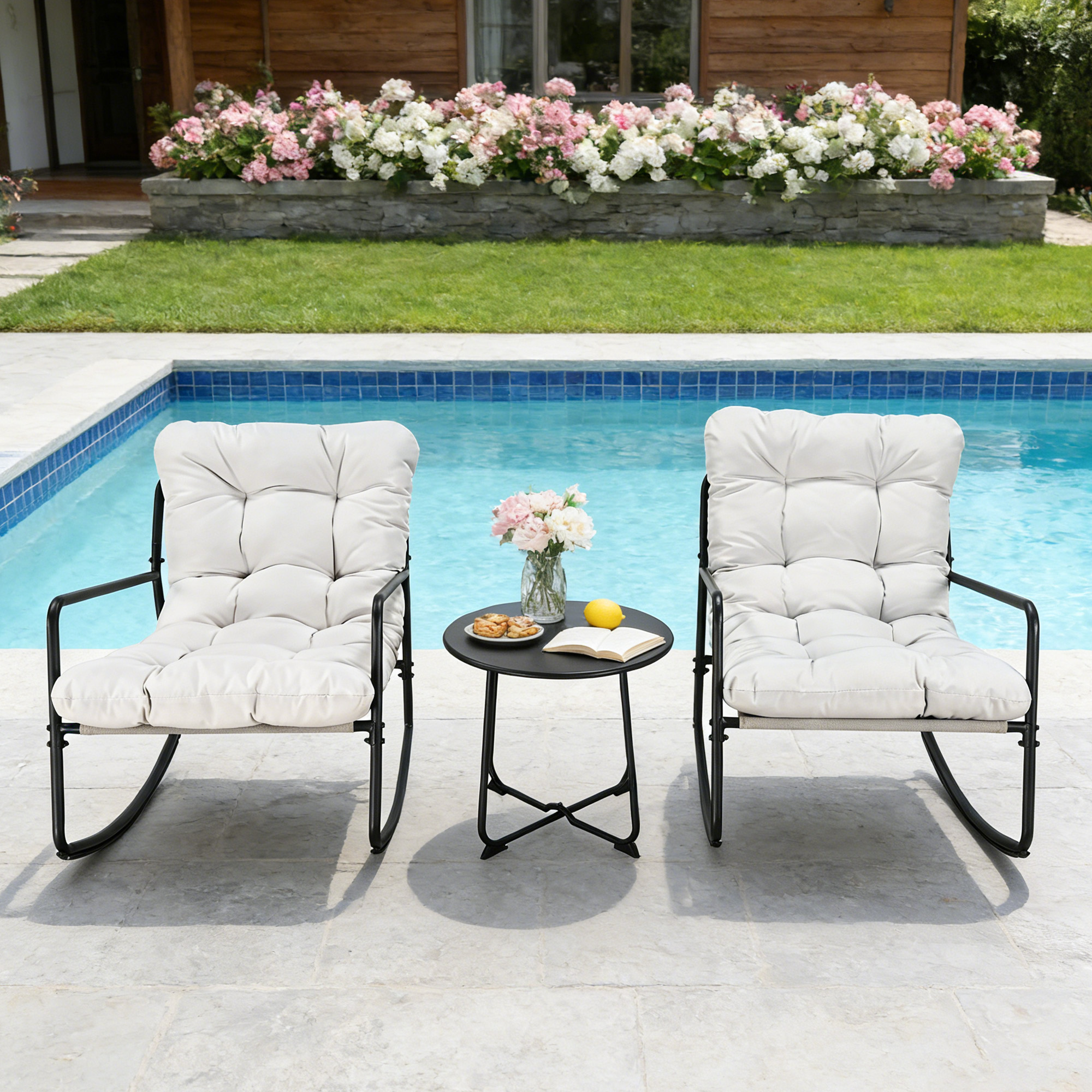 Two cushioned metal rocking chairs with a small round table by a poolside garden-Seehill