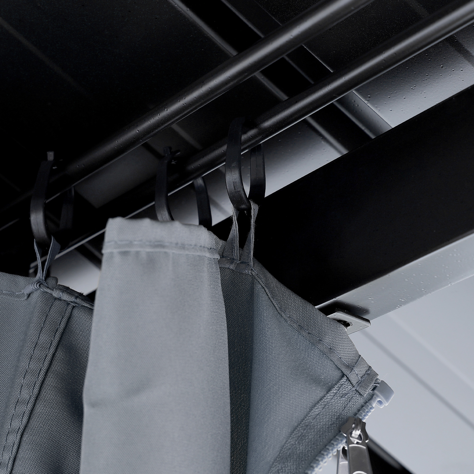 Close-up of gray fabric curtains hanging from black metal hooks on a gazebo frame -Seehill
