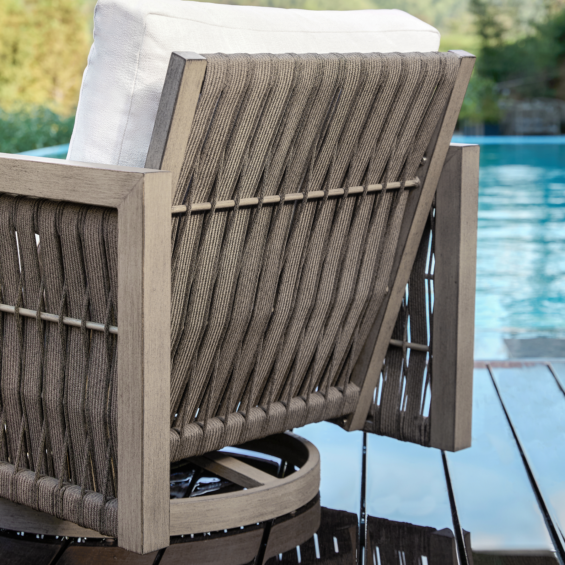Outdoor swivel chair with woven back and cushion, poolside setting - Seehill