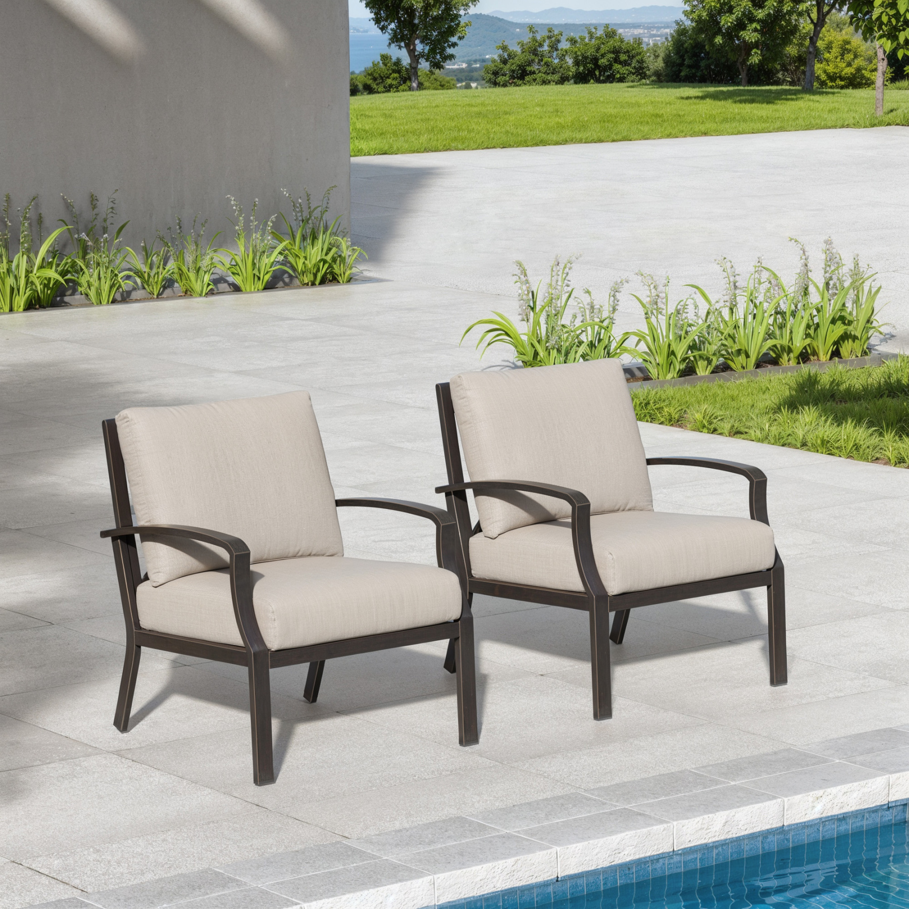 Two cushioned armchairs with dark frames set on a patio near a pool and greenery-Seehill