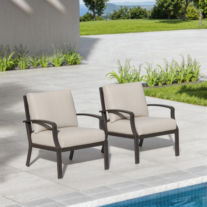 Two cushioned armchairs with dark frames set on a patio near a pool and greenery-Seehill