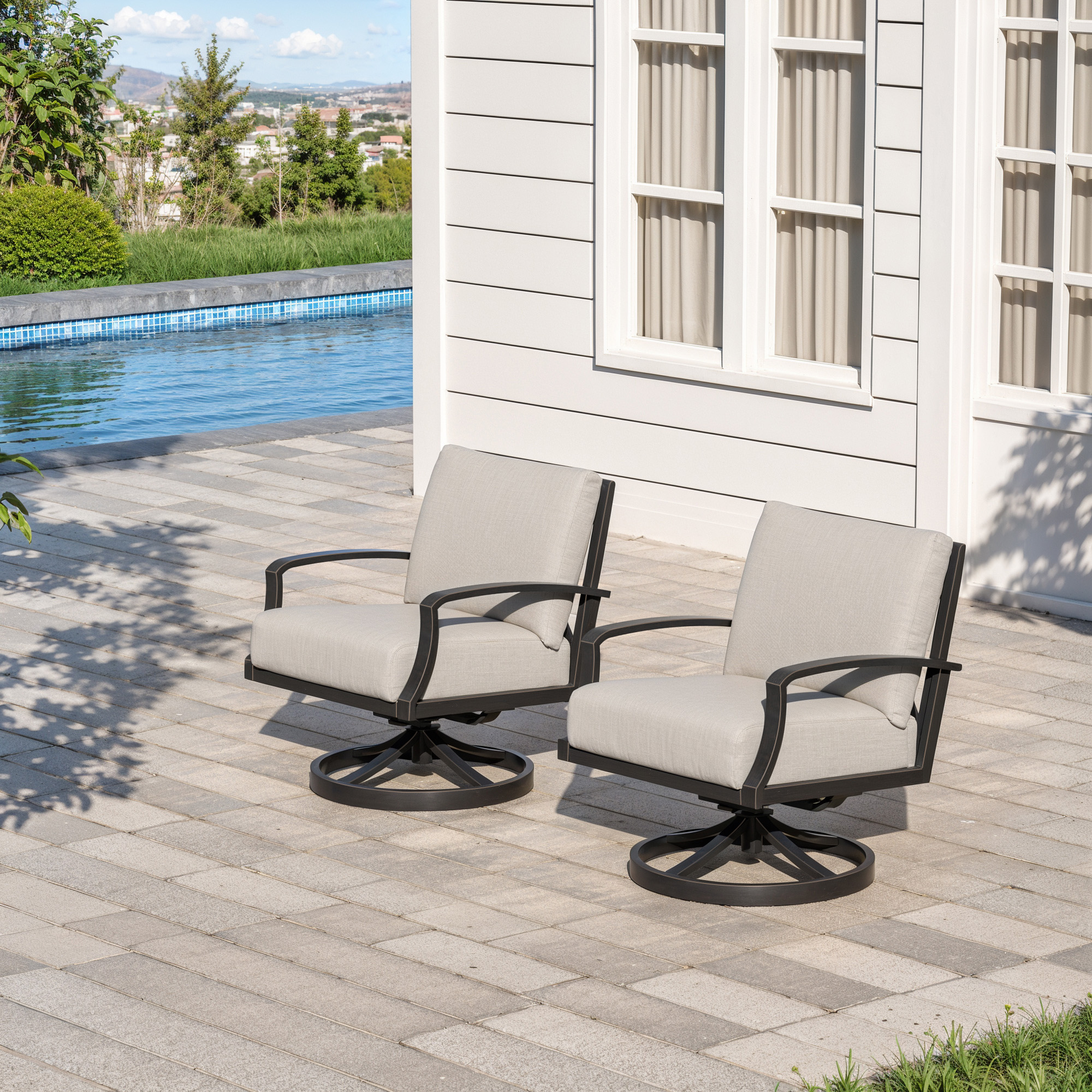 Two wide cushioned outdoor swivel chairs on a patio near a pool and house wall-Seehill