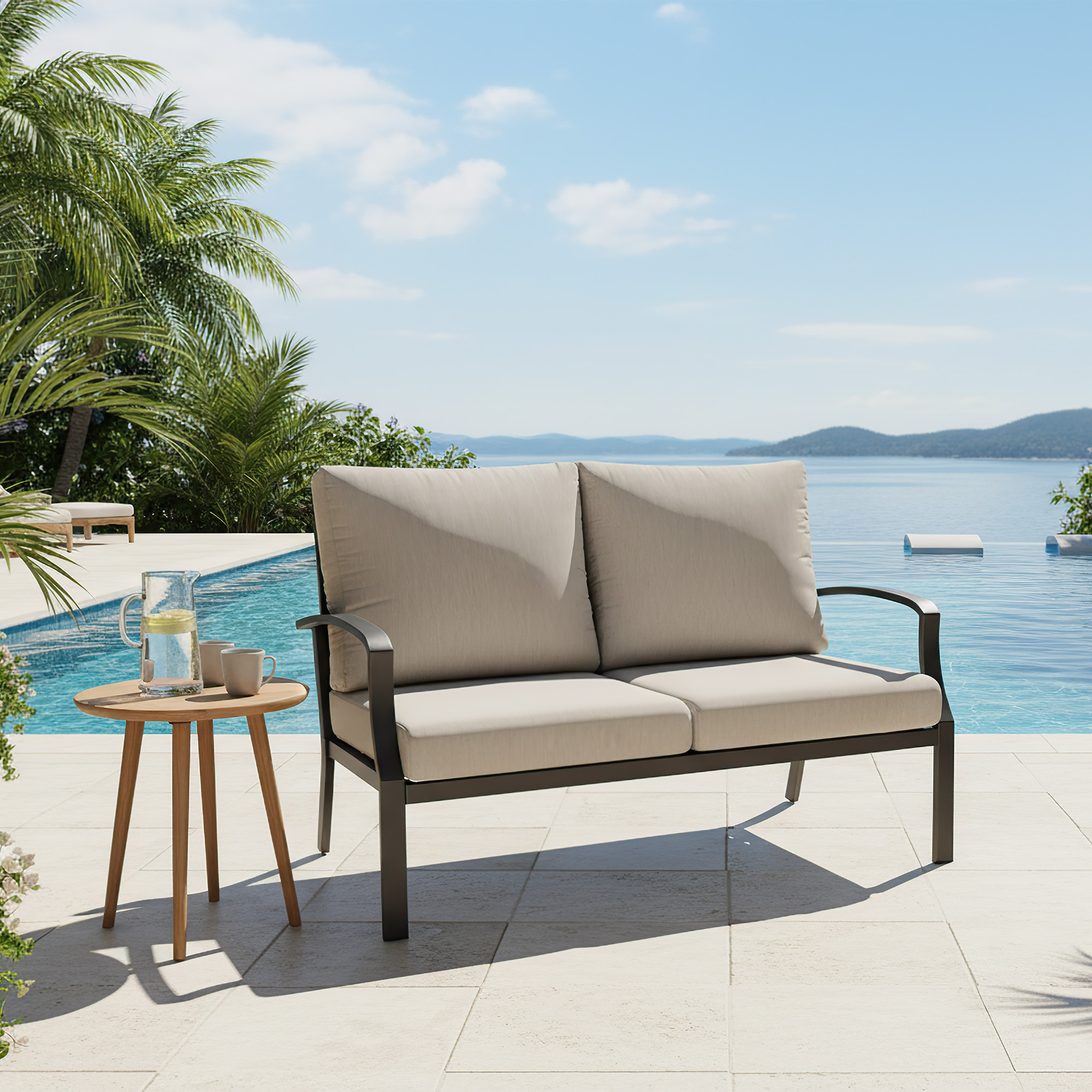 Outdoor loveseat sofa with beige cushions by the pool under a clear blue sky -Seehill