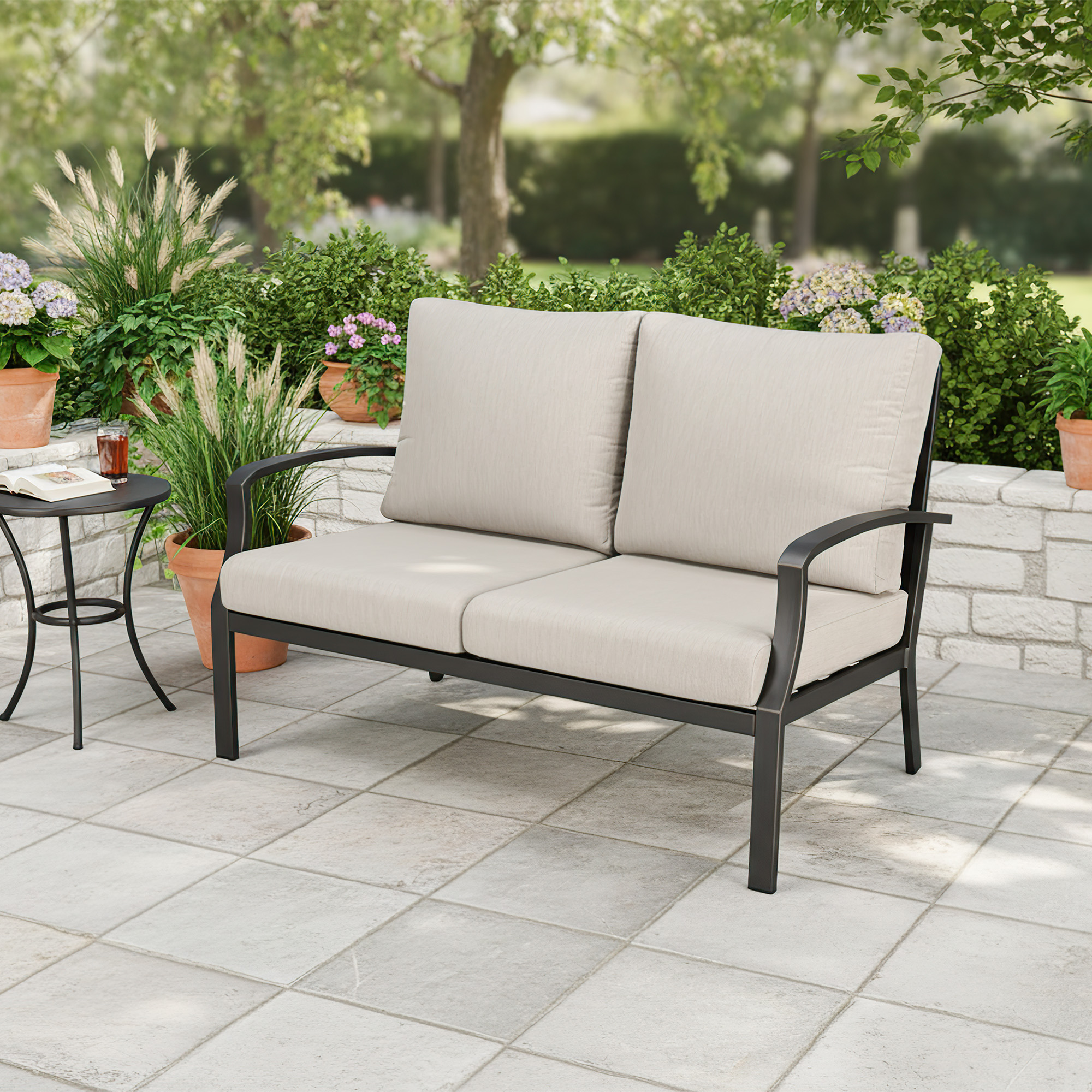 Outdoor patio loveseat sofa with beige cushions and black metal frame on stone tiles-Seehill