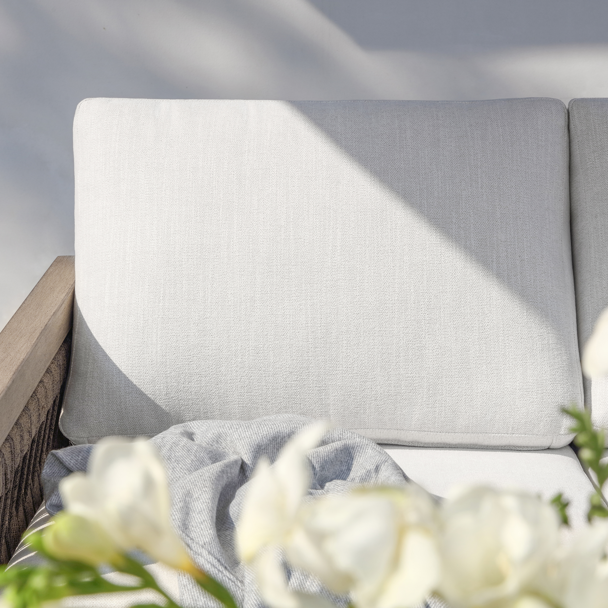 Experience the light gray outdoor sofa cushion with wooden frame and floral decor in our elegant outdoor collection. - Seehill
