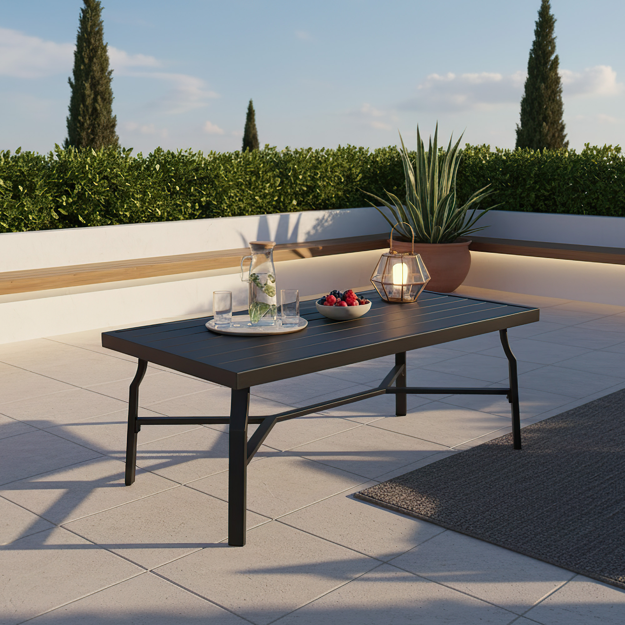 Outdoor patio scene with a rectangle coffee table holding a pitcher and fruit bowl -Seehill