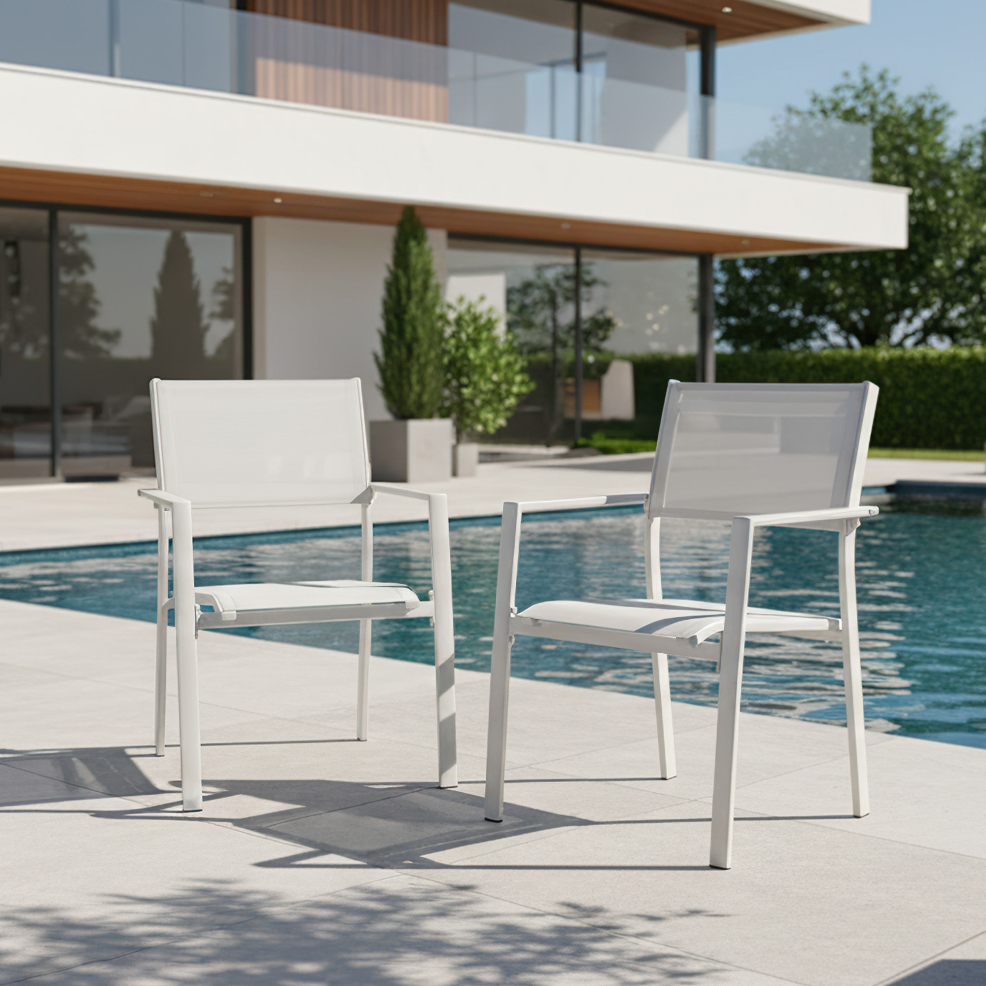 Two white stackable patio dining chairs with textile seats by a poolside setting -Seehill
