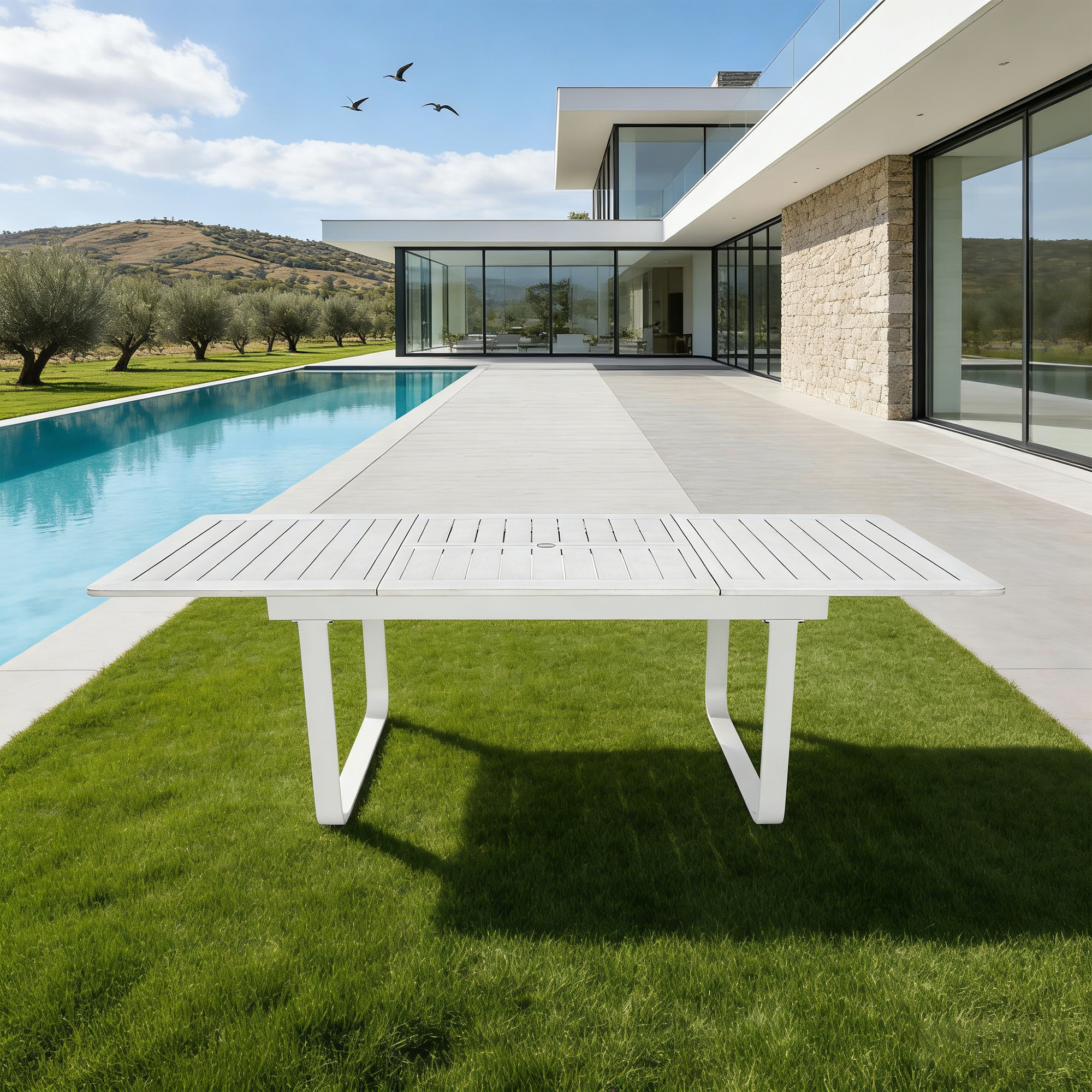 White expandable patio dining table with U-shaped legs on grass near modern pool-Seehill