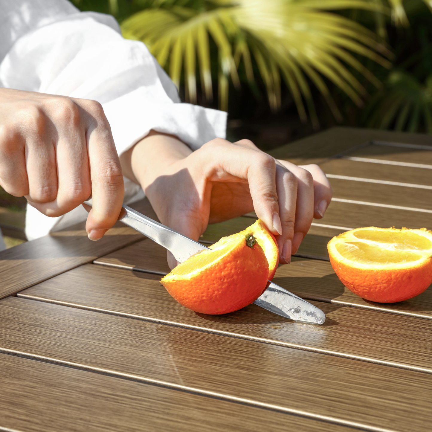 Stainless steel fruit knife slicing orange outdoors - Seehill