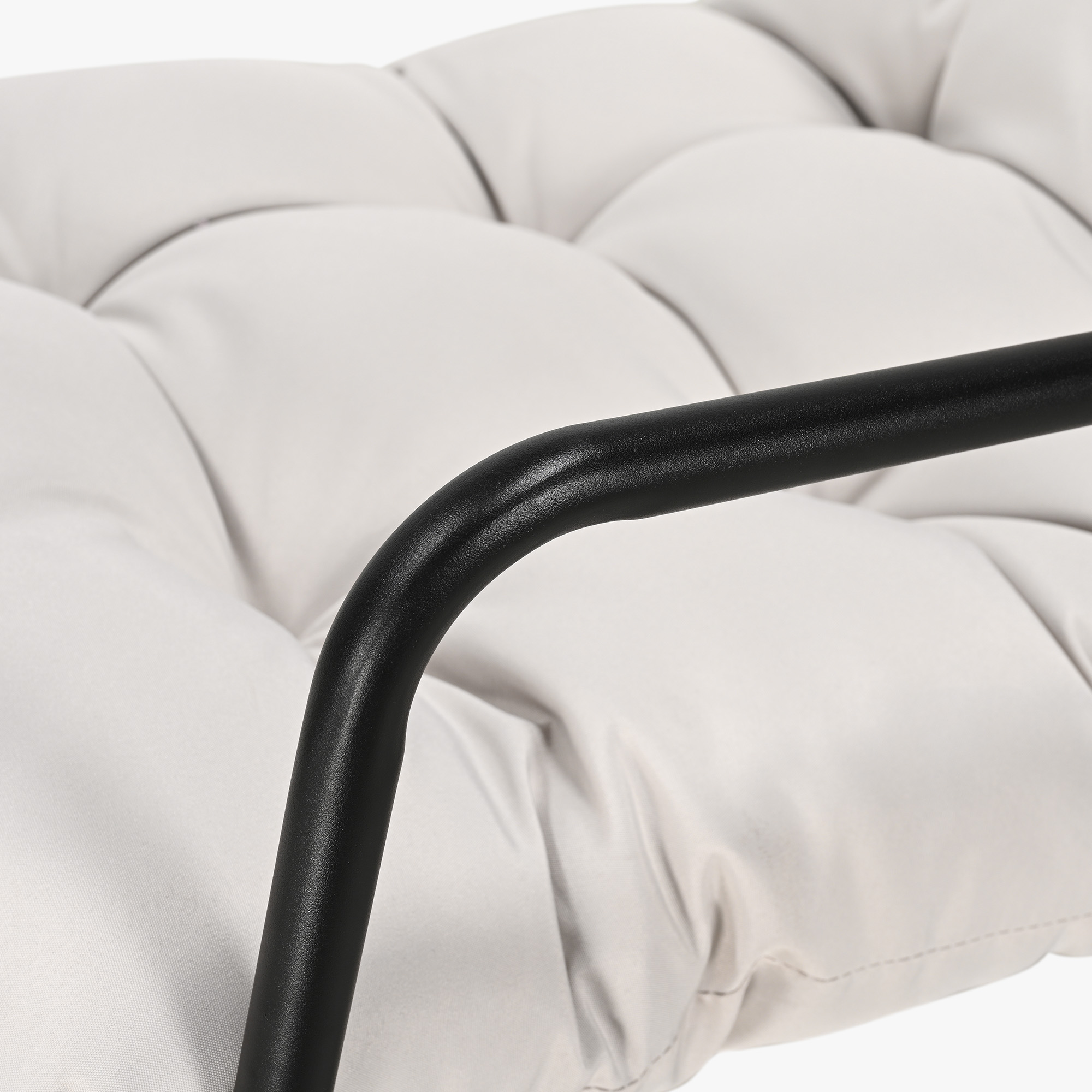 Close-up of black metal armrest and tufted white cushion of modern patio rocking chair -Seehill