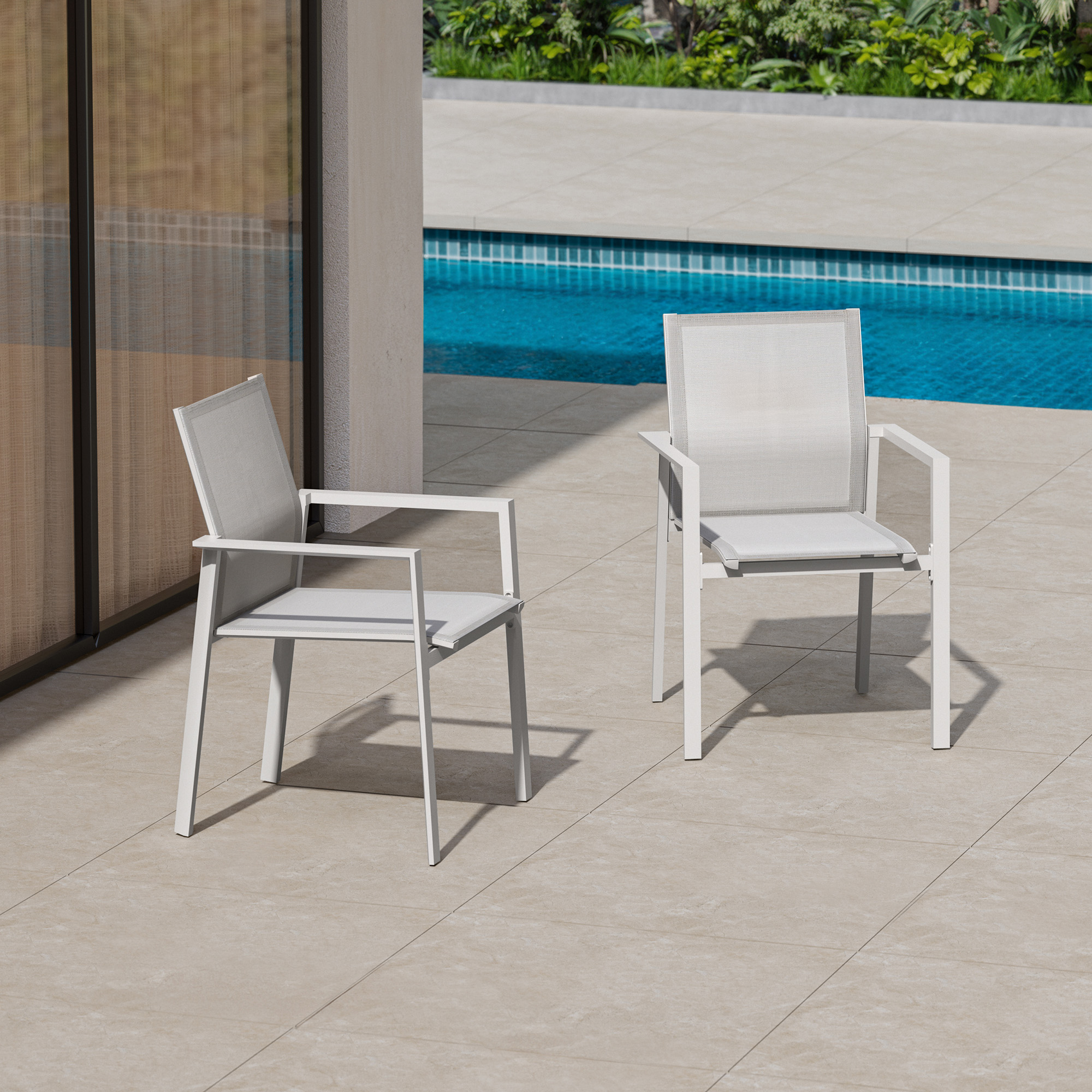 Two white stackable patio dining chairs with full backs by a pool on tiled flooring-Seehill