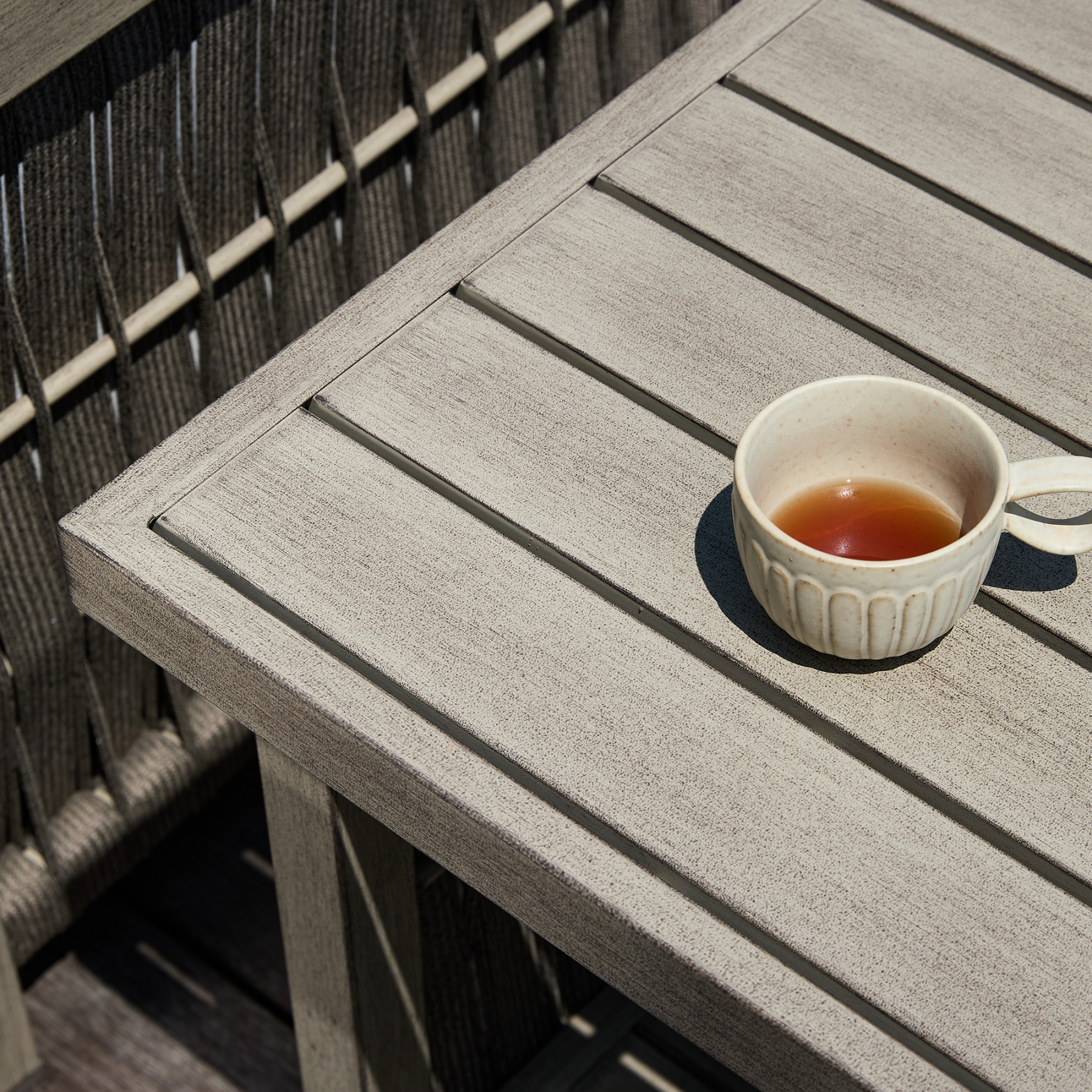 Outdoor wooden table with cup of tea, modern patio furniture - Seehill