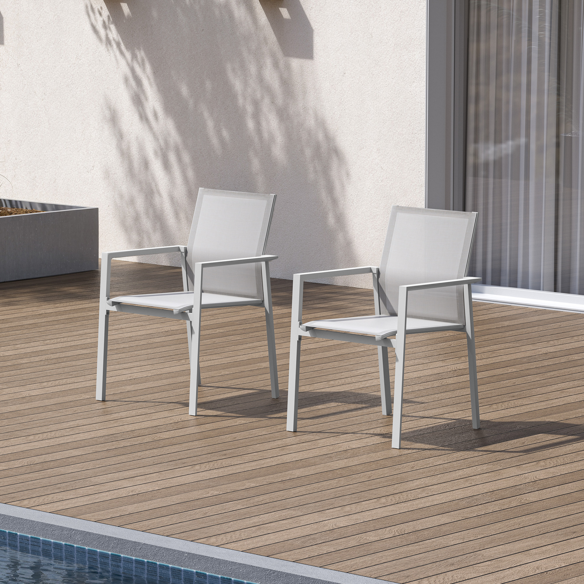 Two white stackable patio dining chairs on wooden deck near pool and sliding door -Seehill