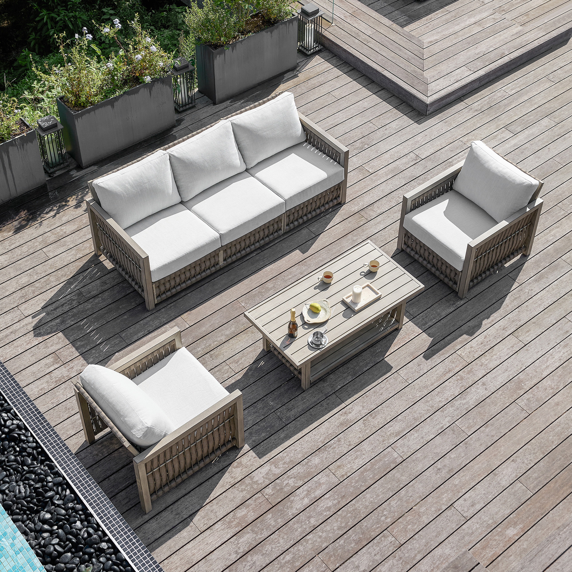 This image highlights the modern outdoor wicker sofa set with white cushions of this refined outdoor patio design. - Seehill