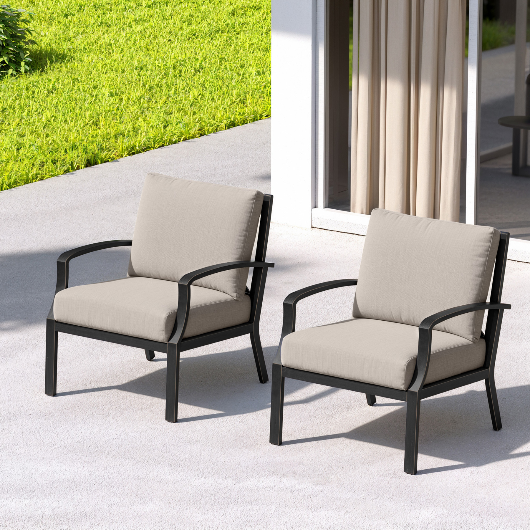Two cushioned deep-seating patio armchairs with black metal frames on a sunny patio-Seehill