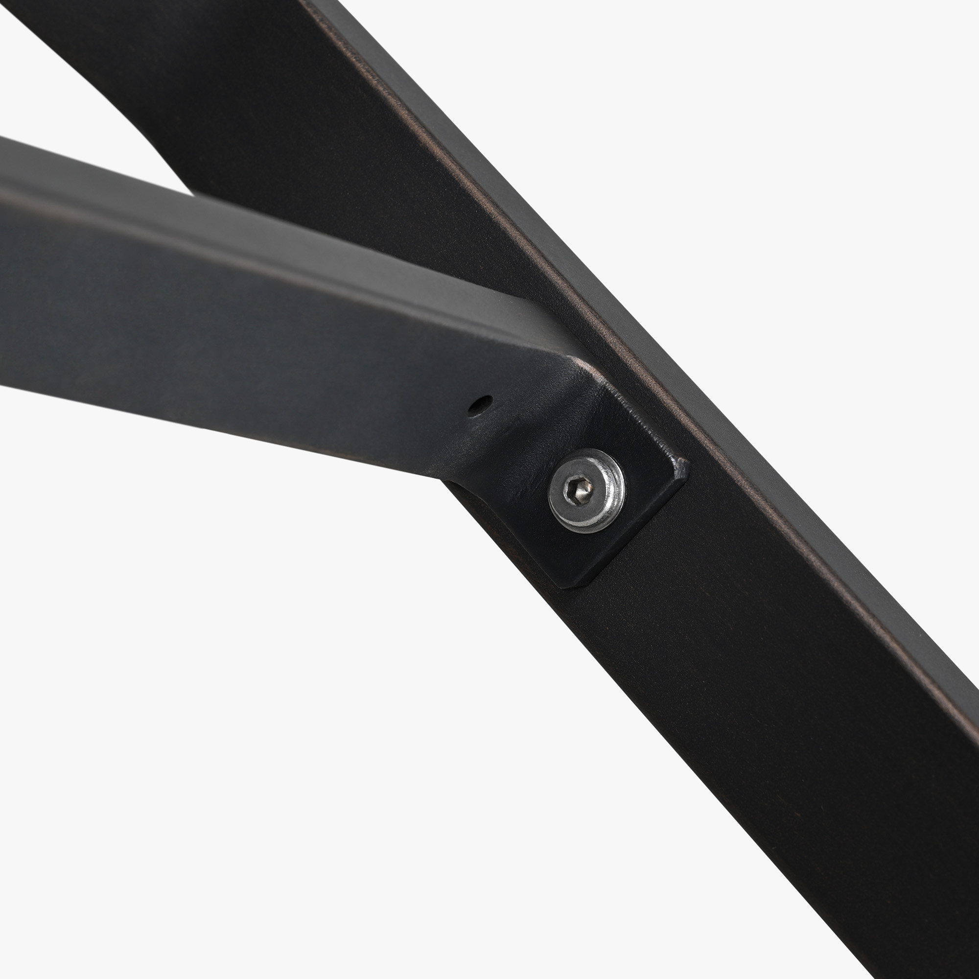 Close-up of black metal frame joint with bolt detail on patio coffee table -Seehill