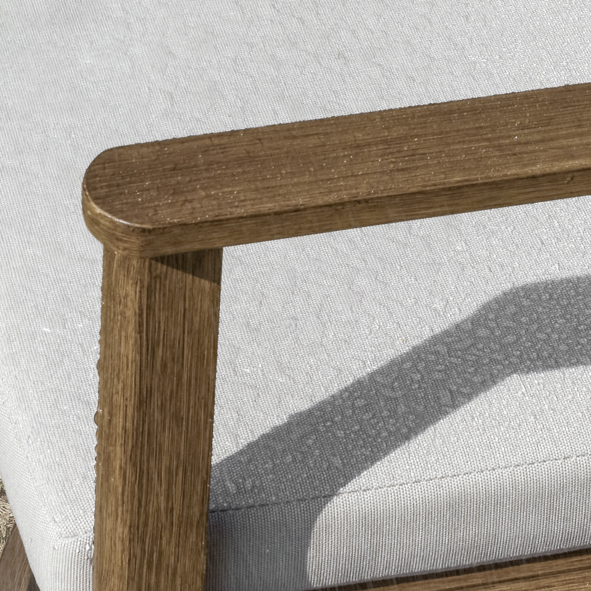Explore the weathered teak armrest with rounded edge on light gray textured fabric of the graceful Piece Outdoor set. - Seehill