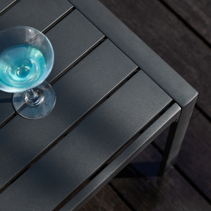 Modern outdoor side table with sleek gray finish and glass drink. - Seehill