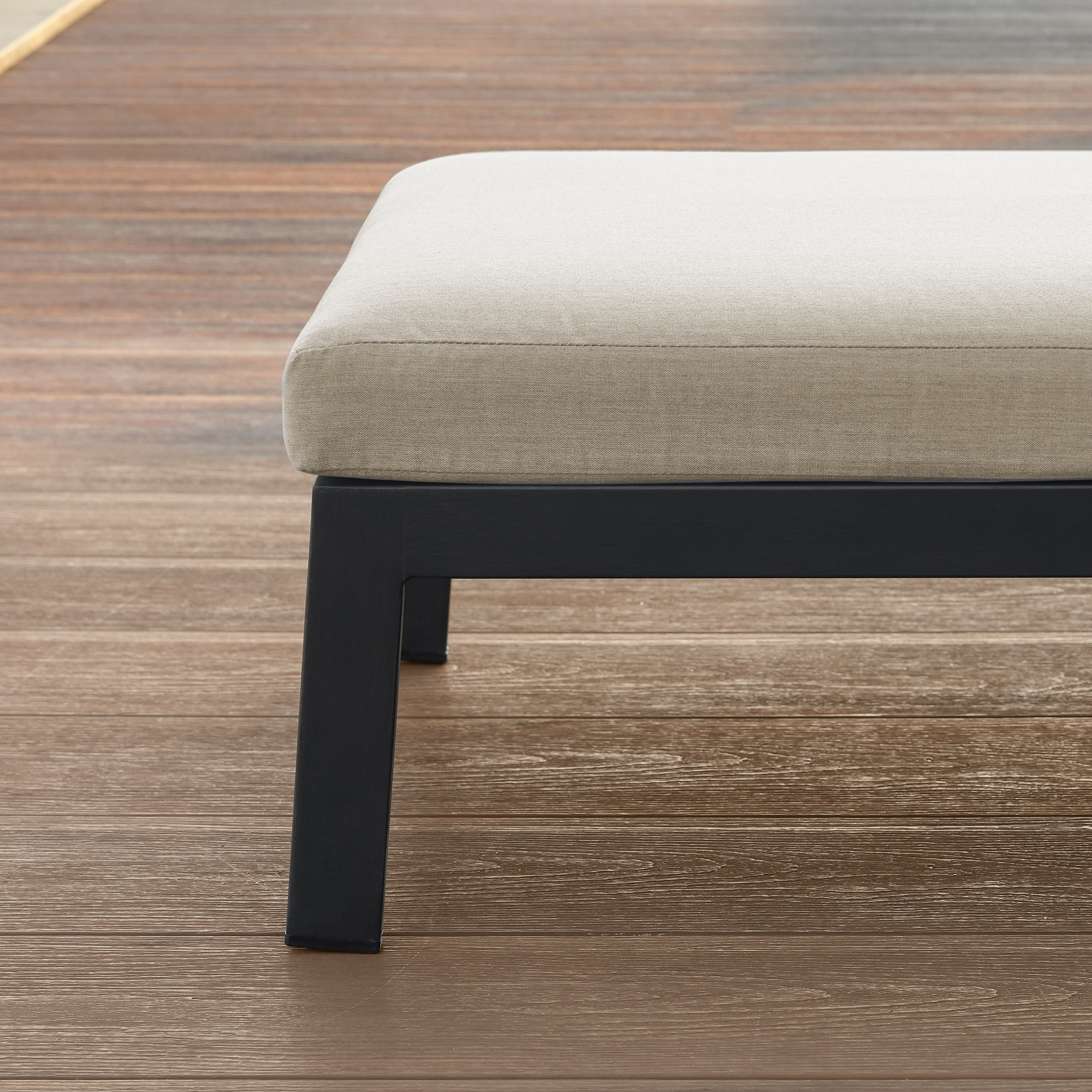 Close-up of patio lounge chair leg with beige cushion on wooden deck-Seehill