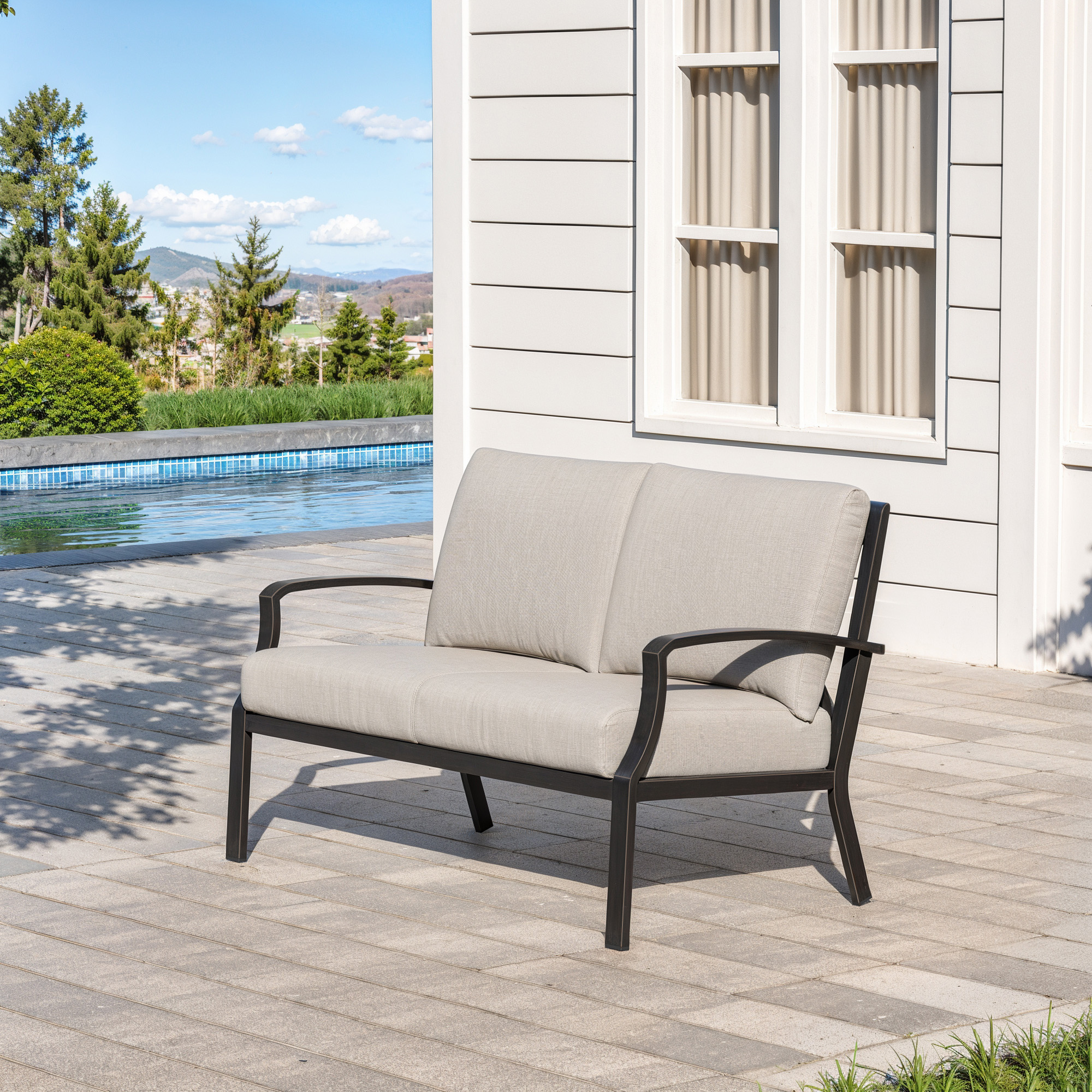 Outdoor loveseat sofa with beige cushions and black metal frame by the poolside -Seehill