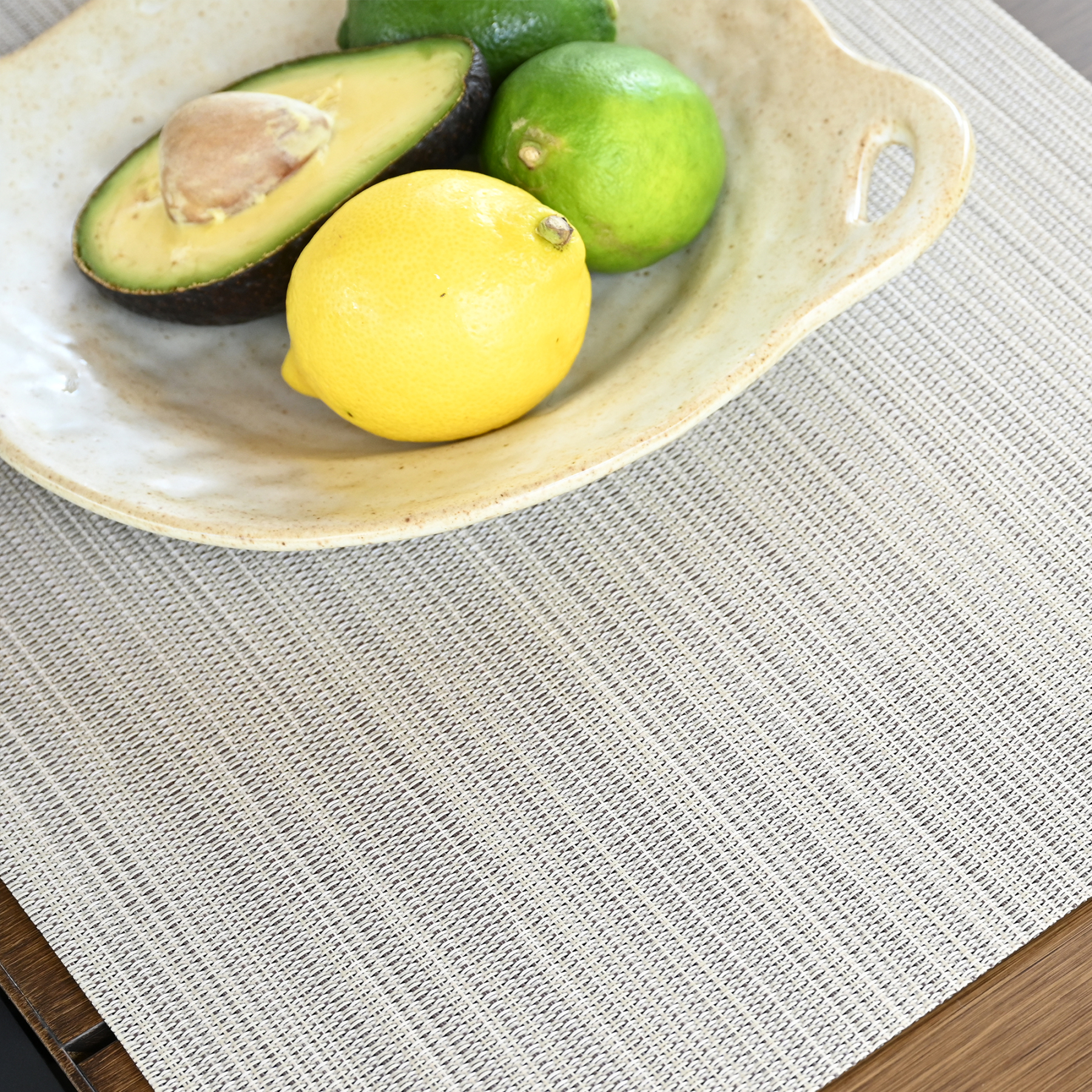 Crafted with a set of four beige versatile clean look placemats displaying a subtle textured pattern on a wooden surface. - Seehill