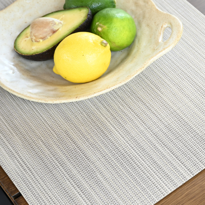 Crafted with a set of four beige versatile clean look placemats displaying a subtle textured pattern on a wooden surface. - Seehill