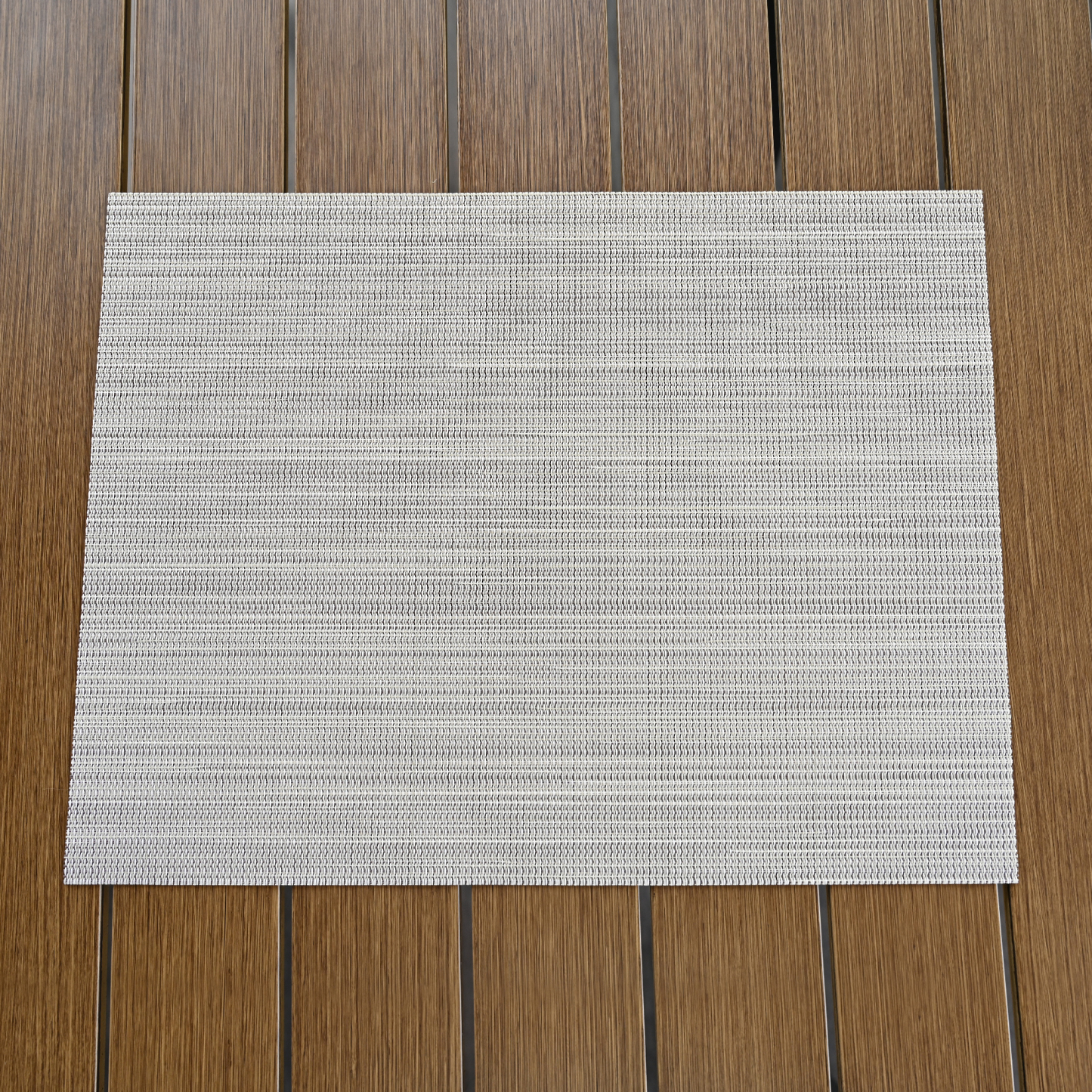 Highlighting a set of four beige versatile clean look placemats with a subtle texture on a wooden surface. - Seehill