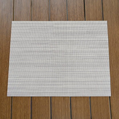 Highlighting a set of four beige versatile clean look placemats with a subtle texture on a wooden surface. - Seehill