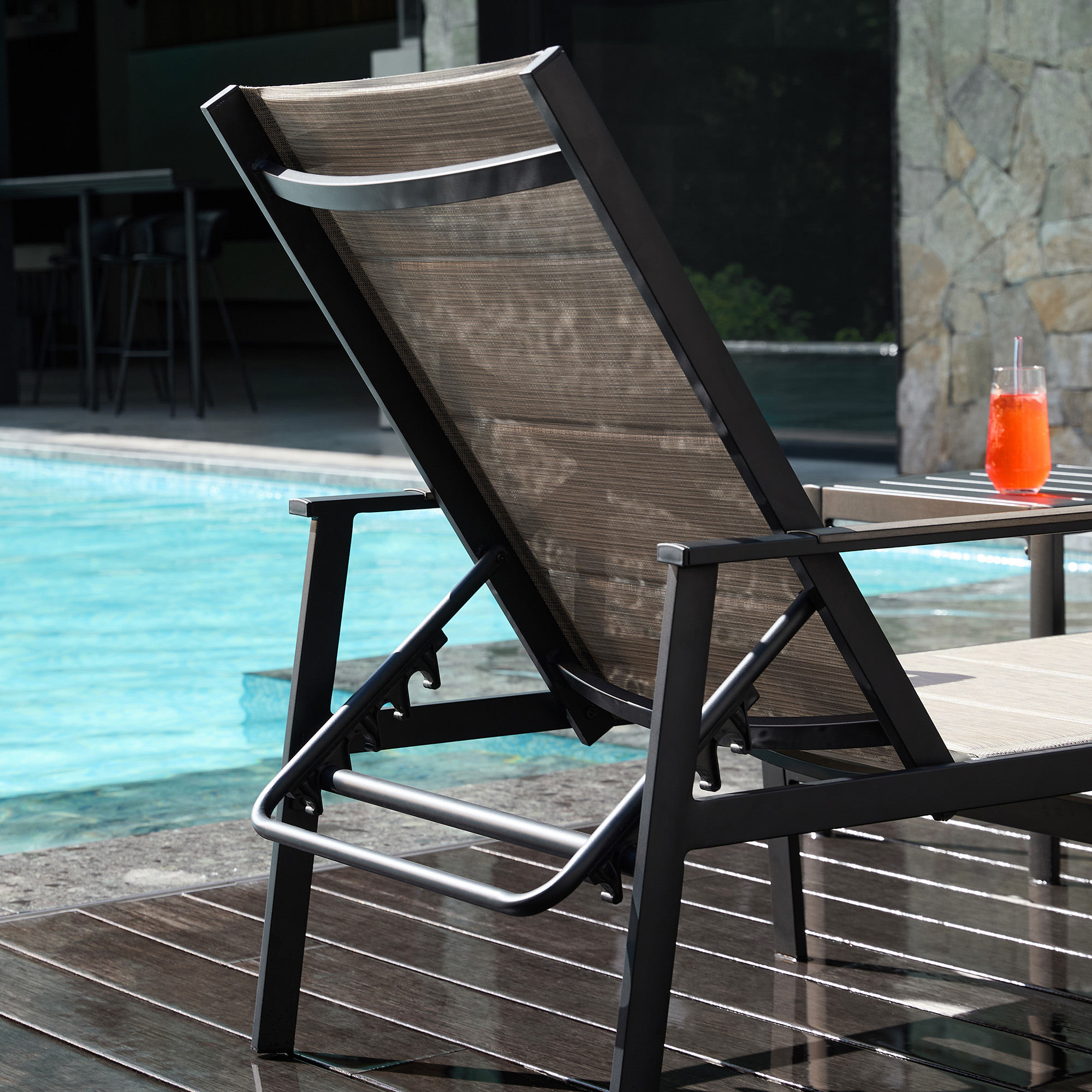 Explore the Outdoor lounge chair with an adjustable back and side table near the pool of the exclusive resort. - Seehill