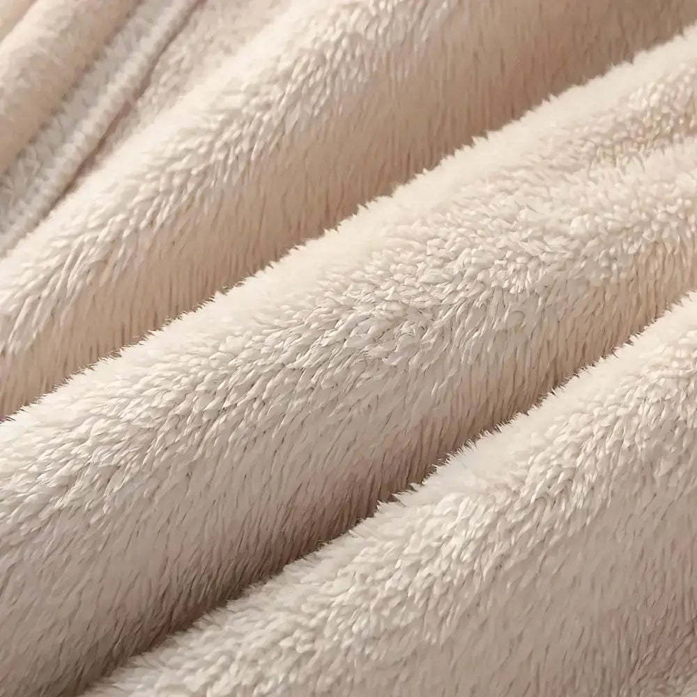 Close-up of a soft plush fabric in a warm off-white or cream color, showing the texture and folds of the material.