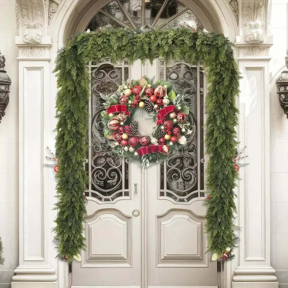 A festive Christmas wreath with red ribbons, ornaments, pinecones, and green foliage hangs on a double front door, framed by a matching green garland draped over an arched doorway.