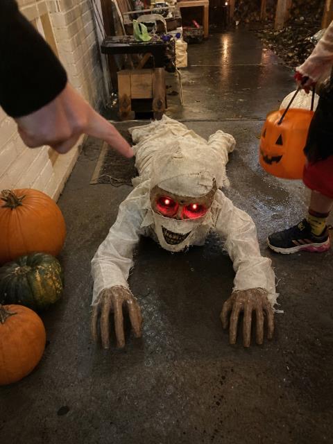 Crawling mummy beside pumpkins during a covered trick-or-treat setup