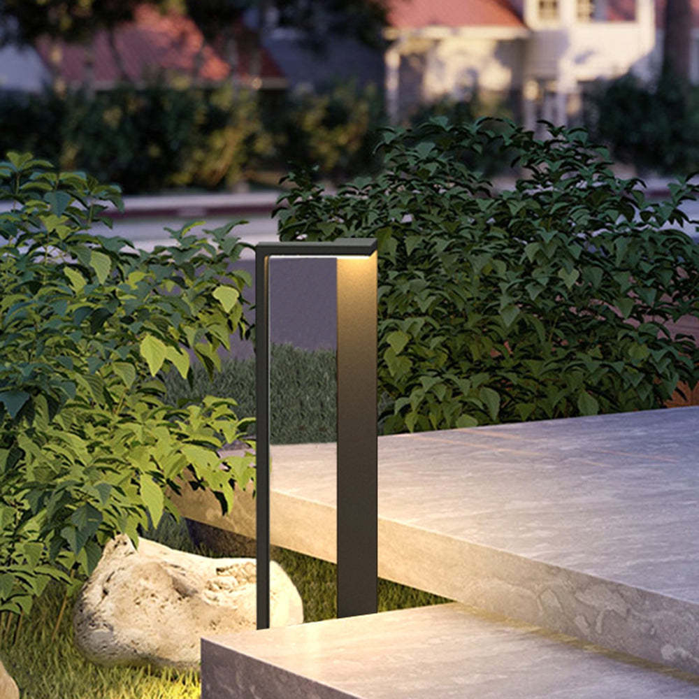 Modern outdoor path light illuminating a garden path