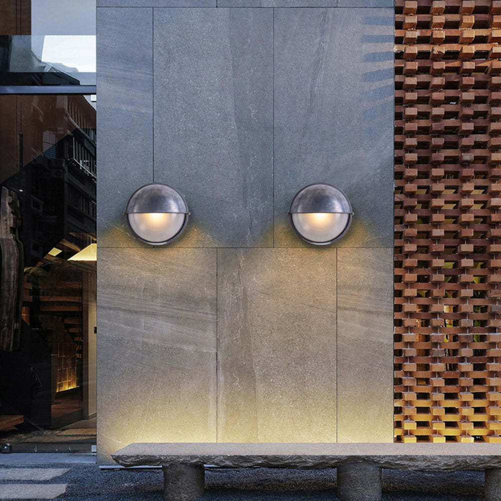 Modern outdoor wall lamps illuminating a stone bench.
