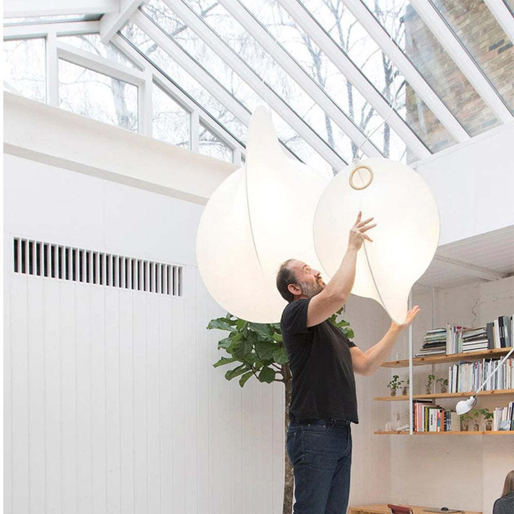 Man adjusting Renée pendant light in modern interior, white fabric
