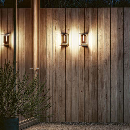 Orr metal & glass solar wall lamps illuminate wood fence.