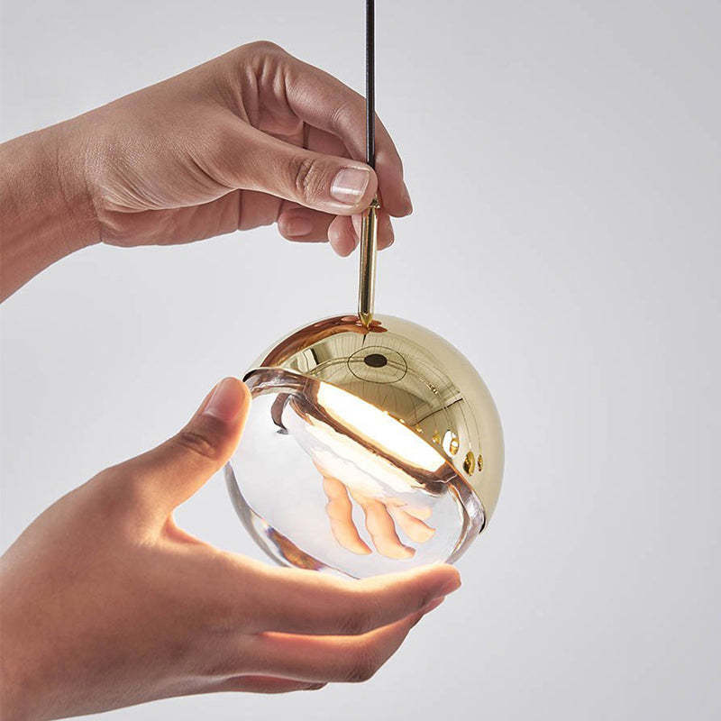 Valentina Pendant Light gold glass ball held by hand