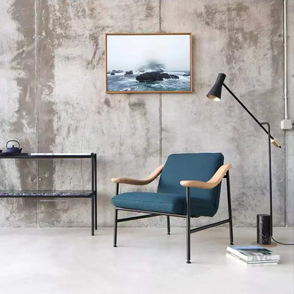 Modern living room interior with a blue chair, floor lamp and artwork.