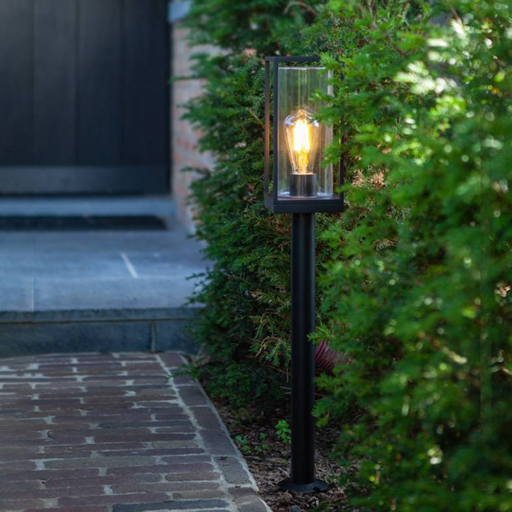 Modern black outdoor path light illuminating a garden pathway