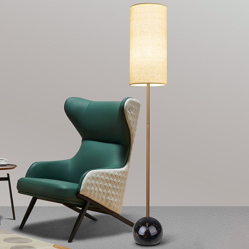 Eryn Cylinder Floor Lamp next to a green armchair in living room
