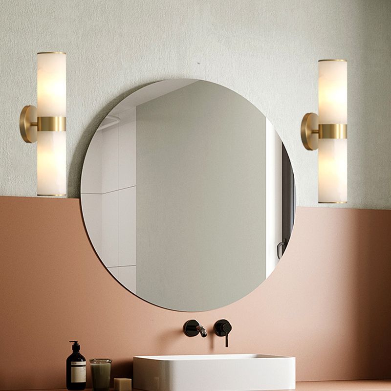 Modern bathroom with brass and stone wall sconces, round mirror