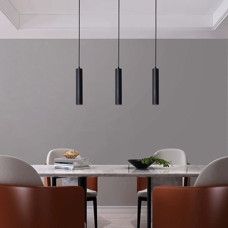 Modern black cylinder pendant lights above a dining table